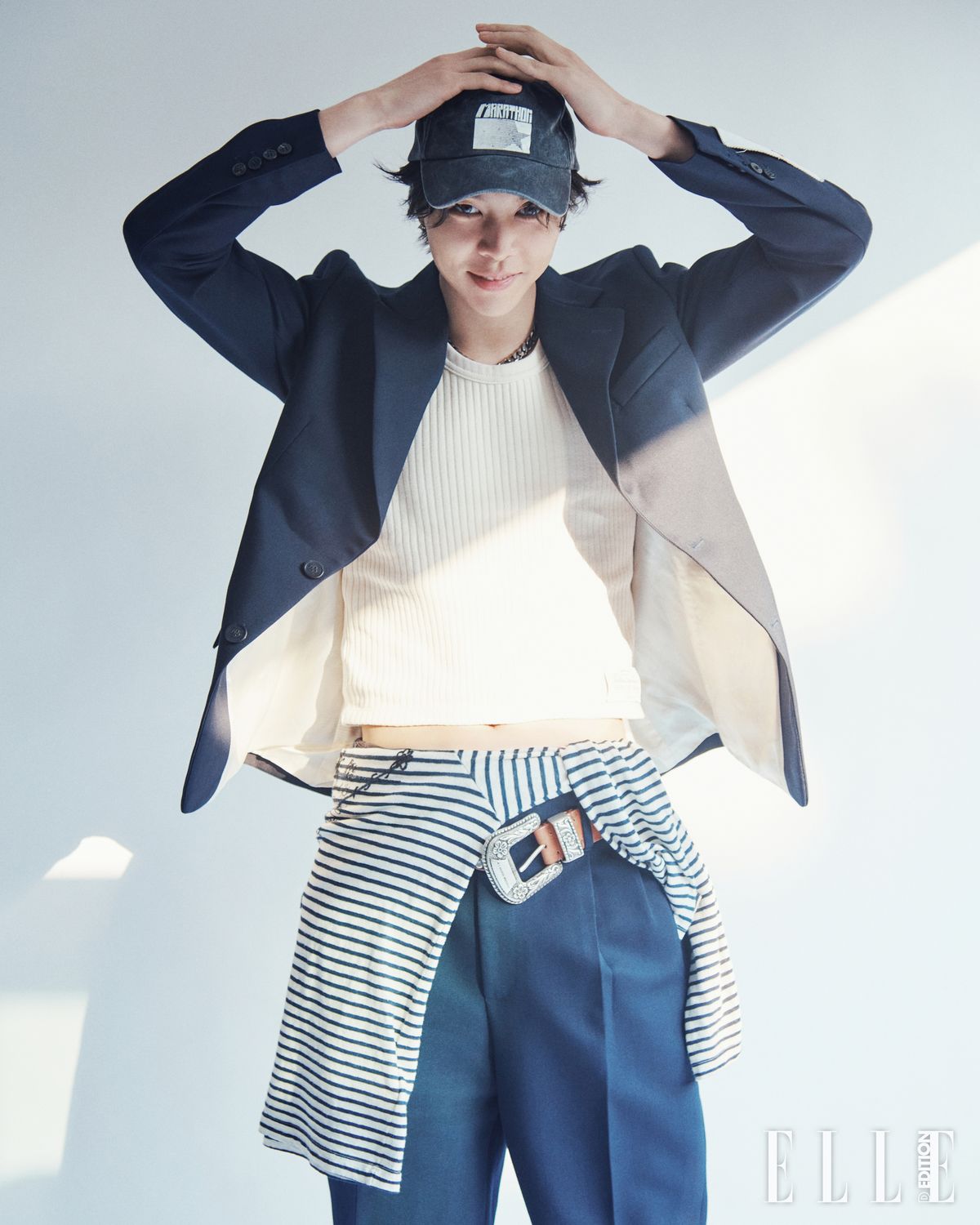 싱글 브레스트 블레이저, 와이드 레그 팬츠, 슬리브리스 톱, 허리에 묶은 스트라이프 티셔츠, 버클 장식이 달린 브라운 레더 벨트, 실버 체인 네크리스는 모두 Golden Goose.