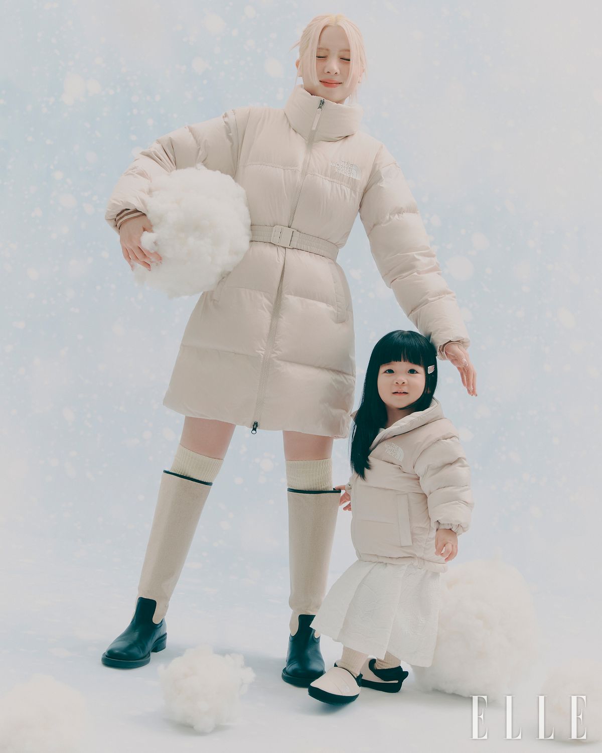 다솜이 착용한 눕시 벨티드 다운 코트는 The North Face. 터틀넥 니트와 니삭스, 슈즈는 모두 스타일리스트 소장품. 이로가 착용한 키즈 1996 에코 눕시 RDS 다운 재킷과 키즈 눕시 뮬은 모두 The North Face. 원피스는 스타일리스트 소장품.