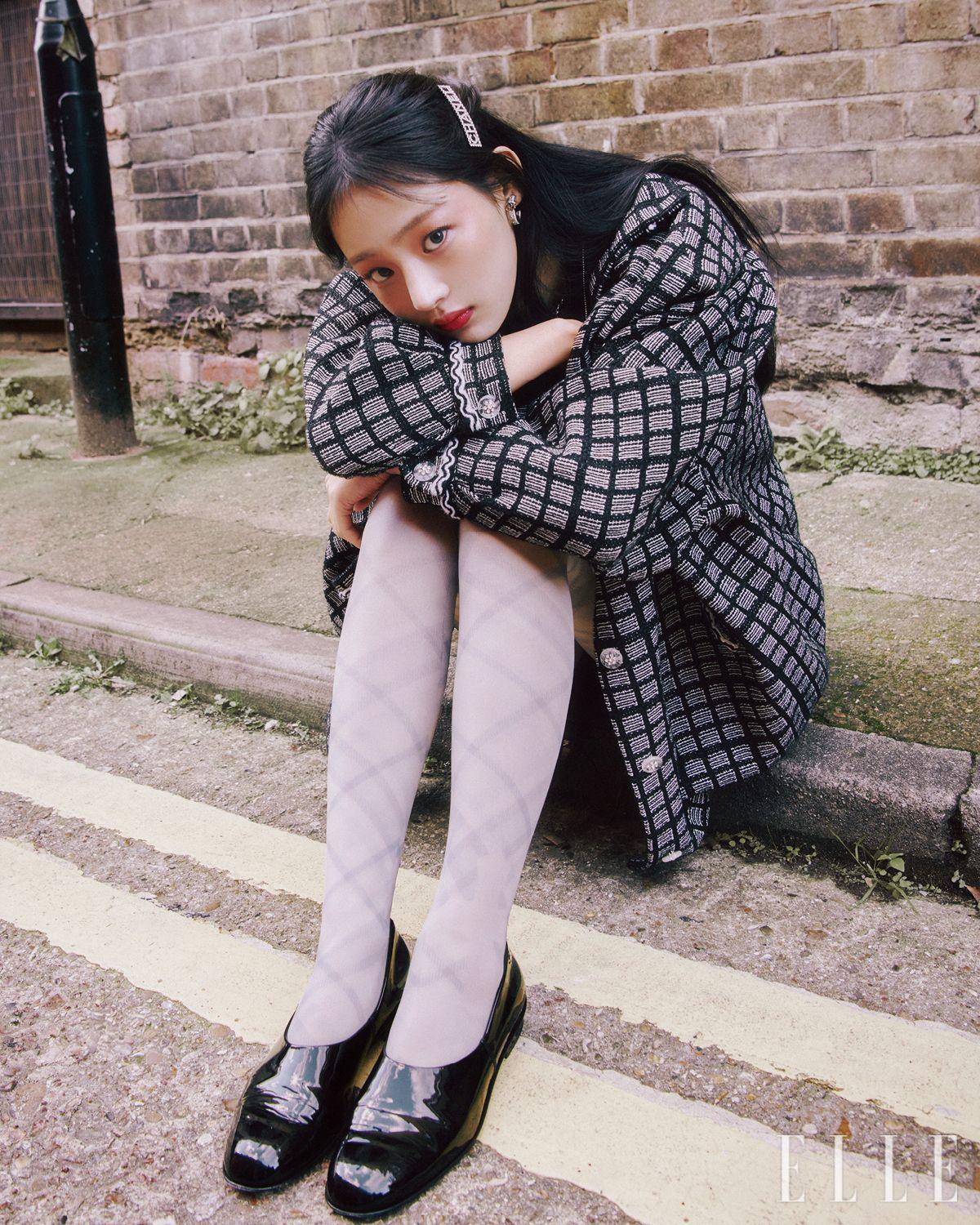 자유로운 ‘런던 걸’ 무드를 뽐내는 민지. 레 베쥬 쿠션과 N°1 DE CHANEL 레드 까멜리아 립 앤 치크 밤, 2 헬시 핑크로 섬세하게 빛나는 윤기 피부를 완성한다. 레 베쥬 아이섀도우 팔레트, 웜으로 자연스러운 음영만 부여한 뒤 스틸로 쑤르씰 오뜨 프레시지옹, 154 블롱 땅드르로 정교한 아이브로를 그려 내추럴하지만 힘 있는 인상을 연출한다. 런던이라는 도시의 다채로운 매력과 부합할 루쥬 코코 플래쉬, 91 보헴으로 입술을 라즈베리빛으로 물들인다. 사용 제품은 모두 Chanel. 블랙 후디드 점프수트와 코트, 블랙 페이턴트 슈즈, 헤어핀과 액세서리는 모두 Chanel. 체크무늬 타이츠는 스타일리스트 소장품.
