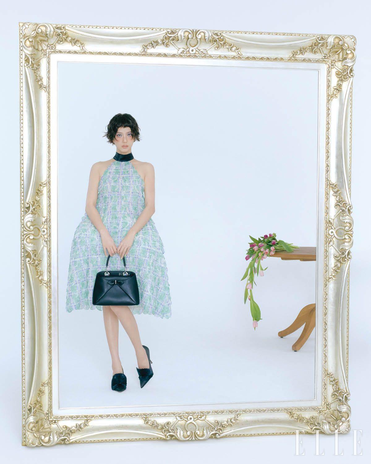 지수가 입은 구조적 형태가 인상적인 엠브로이더리 스캘럽 드레스, 블랙 카프스킨 스몰 디올 시갈 백, 슈즈는 모두 Dior. 