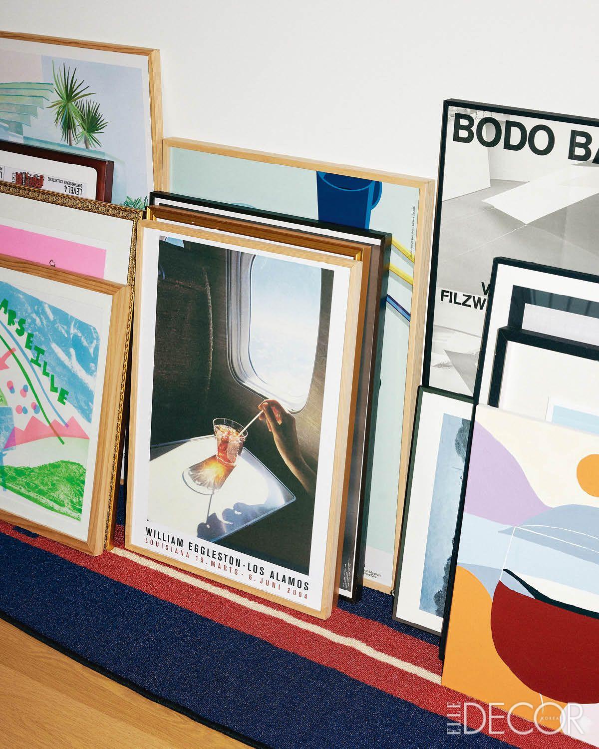 영감을 주는 전시 포스터와 아트워크를 프레임에 넣어 모아둔 거실 바닥. 