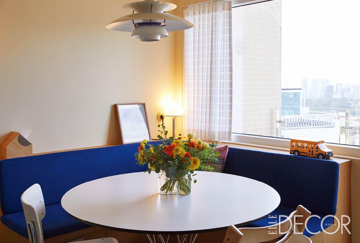 파란 커버의 빌트인 소파와 이사무 노구치 디자인의 라운드 테이블, 알바 알토의 화병, 루이스폴센의 램프가 어우러진 다이닝 공간.