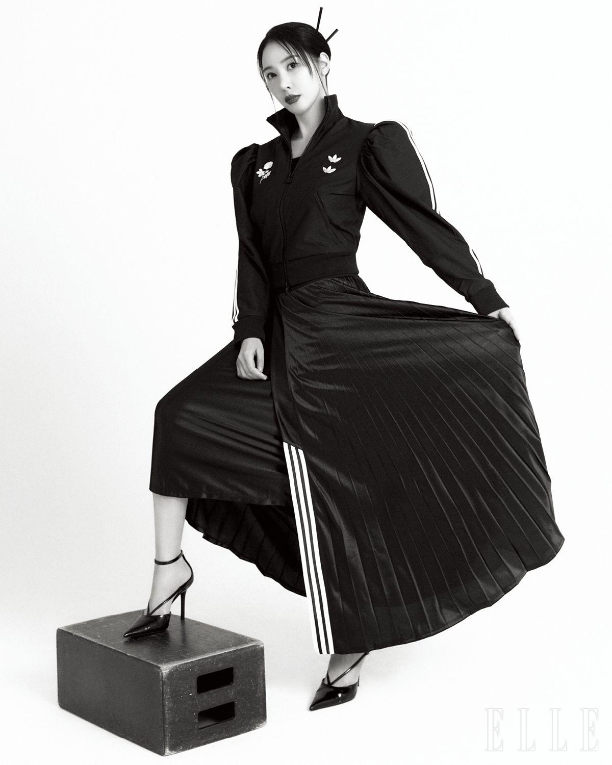 트랙 재킷과 플리츠스커트는 모두 Willy Chavaria x Adidas Originals by MUE. 