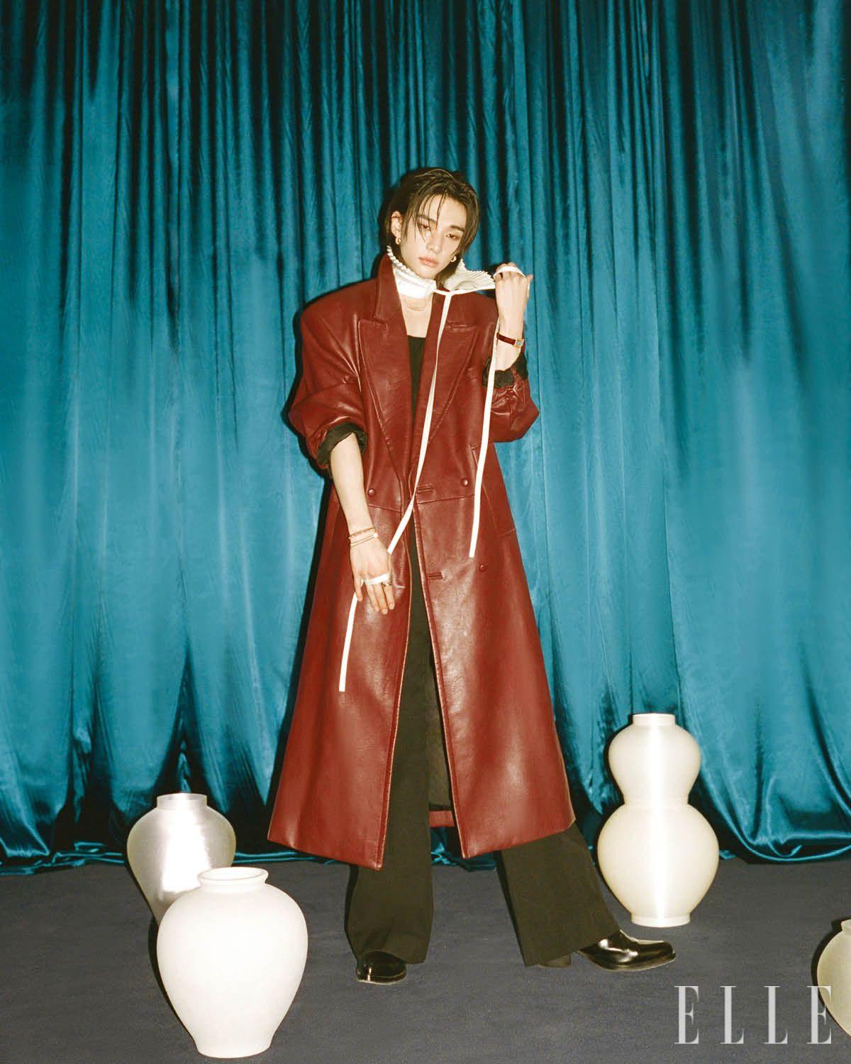 핑크골드에 핑크 칼세도니를 세팅한 클래쉬 드 까르띠에 이어링과 네크리스, 다크 브라운 앨리게이터 레더 스트랩의 스몰 탱크 아메리칸 워치, 오른손에 착용한 화이트· 핑크· 옐로골드의 트리니티 링과 핑크골드 클래쉬 드 까르띠에 스몰 & 미디엄 브레이슬릿은 모두 Cartier. 레더 롱 코트는 Bonbom. 부츠는 Rick Owens. 이너 웨어 톱과 팬츠, 플리츠 디테일의 타이는 모두 스타일리스트 소장품. 서로 다른 크기를 쌓아 올린 달항아리와 왼쪽 뒤편의 달항아리는 모두 Seasoning.objet.