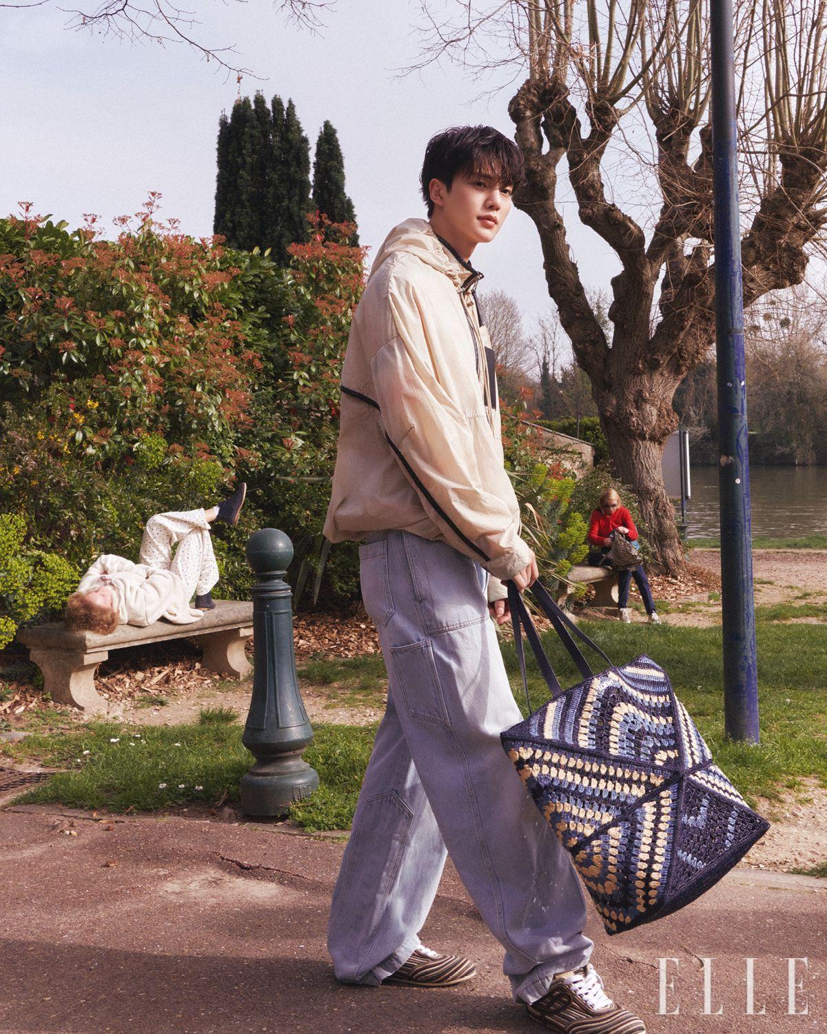 라이트 베이지 컬러 아노락 점퍼와 데님 팬츠, 라피아 소재의 퍼즐 폴드 토트백, 스니커즈는 모두 Loewe.