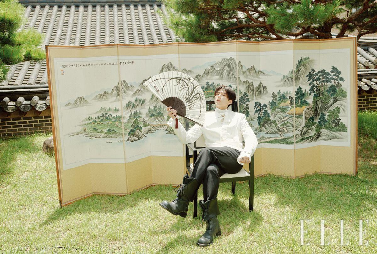 재킷은 Taekh. 새틴 셔츠와 스카프는 모두 Lemeteque. 블랙 팬츠는 Maison Margiela. 블랙 부츠는 Negativethree. 부채는 Baekoaksoo Hanbok. 오른손과 왼손에 착용한 링은 모두 Hermès.
