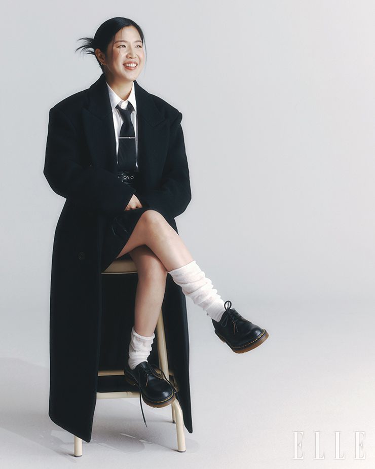 코트는 Max Mara. 스커트는 Courrèges. 슈즈는 Dr. Martens. 셔츠와 타이, 타이 핀, 링 벨트와 삭스는 모두 스타일리스트 소장품.