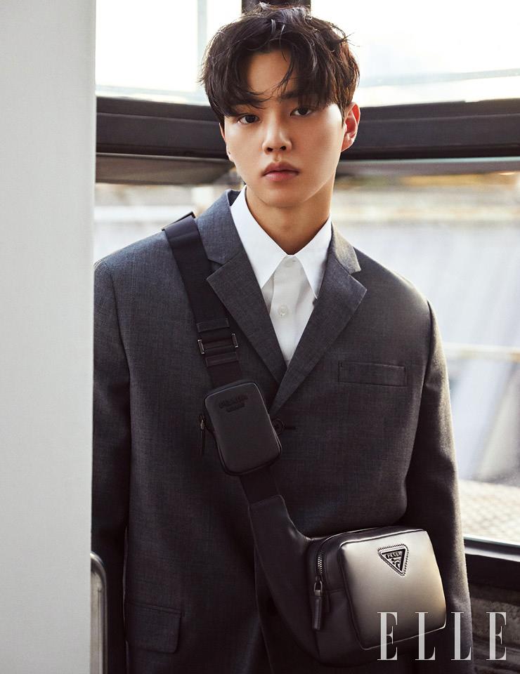 그레이 컬러 스프링 코트와 셔츠, 로고 장식의 레더 크로스백은 모두 Prada.