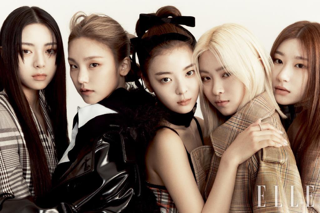 유나가 입은 그레이 체크 재킷. 예지가 입은 바이닐 트렌치코트와 블랙 저지 톱, 폴로 셔츠. 리아가 입은 레드 체크 코르셋 드레스와 버튼 디테일의 울 칼라 스카프. 류진이 입은 오버사이즈 트렌치코트. 채령이 입은 체크 패턴의 테일러드 재킷은 모두 Burberry.