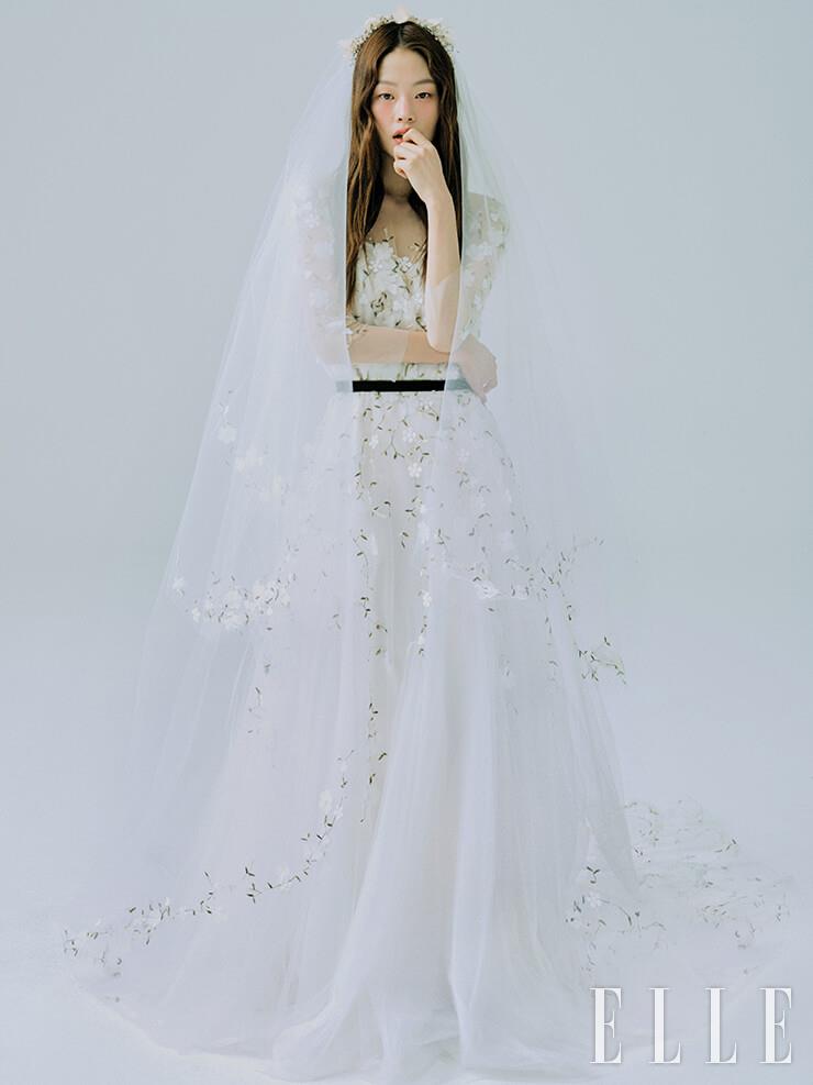 수수한 플로럴 디테일의 드레스와 베일은 모두 Leemyungsoon Wedding. 헤어피스는 Sooya. 