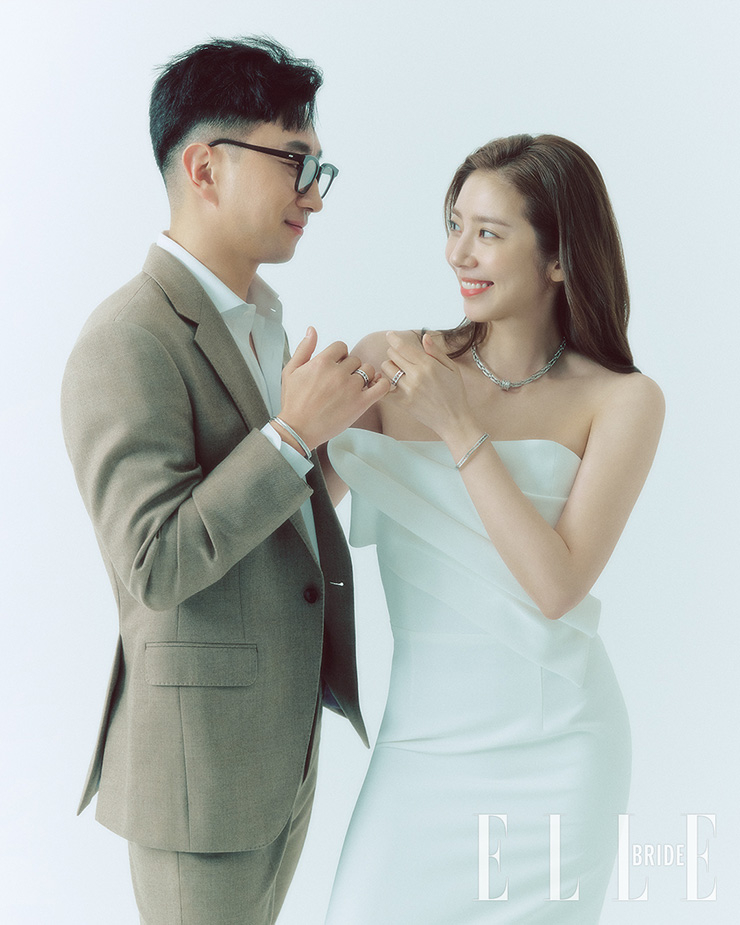 7.19캐럿 다이아몬드가 세팅된 네크리스는 비제로원 락 네크리스, 커플로 착용한 비제로원 브레이슬릿, 브랜드 로고가 로마자로 새겨진 오픈워크 링은 비제로원 밴드 링으로 모두 Bvlgari. 비대칭 장식의 H라인 드레스는 Newhite by Kayla Bennet. 베이지 슈트와 셔츠는 모두 Lord and Tailor, 안경은 개인 소장품.