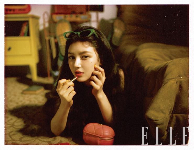 울트라 르 뗑 쿠션으로 시어한 윤기를 더한 다니엘의 피부 위에 펄 없이 보송한 레 꺄트르 옹브르, 308 끌레르-옵스뀌로 뉴트럴 톤의 눈가 음영을 잡아준다. 루쥬 알뤼르 렉스트레, 858호를 입술에 발라 체리 레드빛의 컬러 포인트를 더한다. 사용 제품은 모두 Chanel. 니트 베스트 톱은 Polo Ralph Lauren. 데님 오버올은 스타일리스트 소장품. 핑크색 오벌 미니 백과 볼드한 핑크 초커는 모두 Chanel. 에메랄드 컬러의 워커 부츠는 Dr. Martens. 헤어밴드처럼 연출한 선글라스는 Gentle Monster.