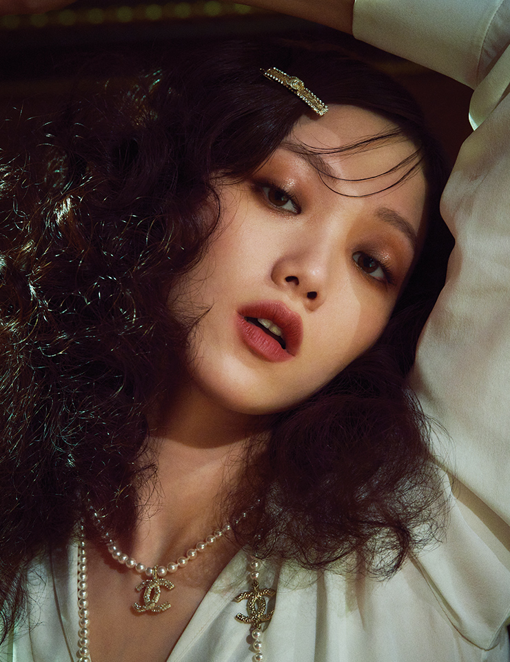 몽상에 빠진 파리지엔처럼! 펄 없이 캐시미어처럼 보송한 레 꺄트르 옹브르, 308 끌레르-옵스뀌로 눈가에 음영을 주고, 2022 홀리데이 메이크업 컬렉션 듀오 뤼미에르를 그 위에 가볍게 두드려 발라 골드 스파클 가득한 광택을 덧입힌다. 웜 핑크빛의 루쥬 알뤼르 렉스트레, 818을 두드리듯 발라 립 라인 바깥으로 자연스럽게 번진 느낌을 연출한다. 사용 제품은 모두 Chanel. 드레이프 블라우스와 팬츠, 진주 네크리스와 헤어핀은 모두 Chanel.