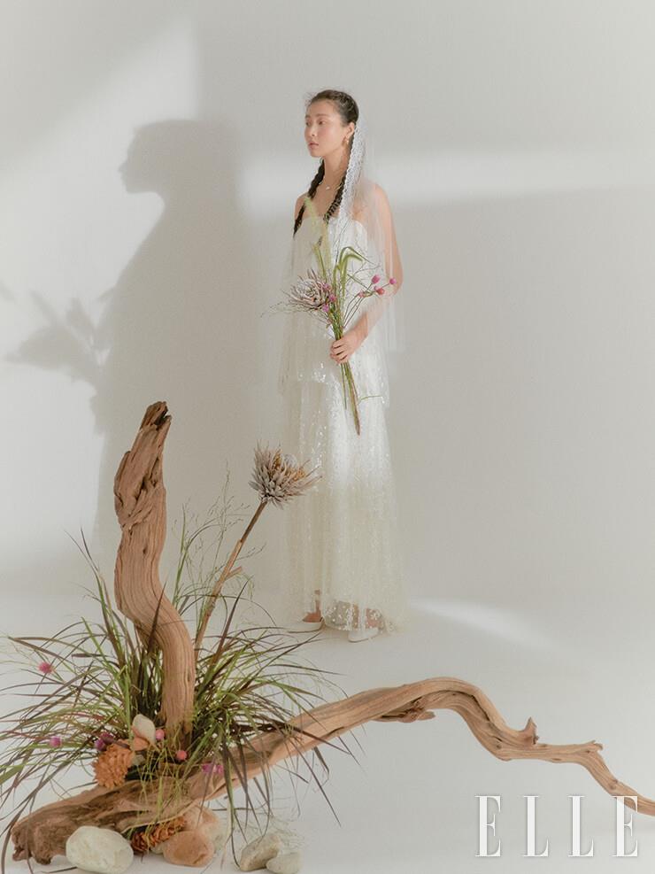 눈이 내린 듯한 티어드 드레스는 Halfpenny London by Soyoo Bridal. 레이스 트리밍 베일은 Abel by K. 골드 이어링과 네크리스는 모두 S_S.il. 슈즈는 Rachel Cox.