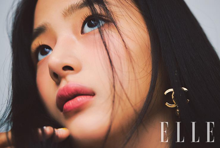 트위드 패턴으로 샤넬만의 클래식함과 현대적인 아름다움을 동시에 선사하는 레 꺄트르 옹브르 트위드, 03 트위드 포브의 앰버 골드와 새틴 코랄 섀도로 눈꺼풀을 가볍게 터치한 뒤, 이니미터블 엑스트렘, 10 퓨어 블랙을 발라 속눈썹을 더 길고 풍성하게 연출한다. 웜 핑크 톤의 루쥬 알뤼르 엑스트레, 818호로 입술을 물들이면 완성. 사용 제품은 모두 Chanel. 더블 C 로고의 후프 이어링은 Chanel.