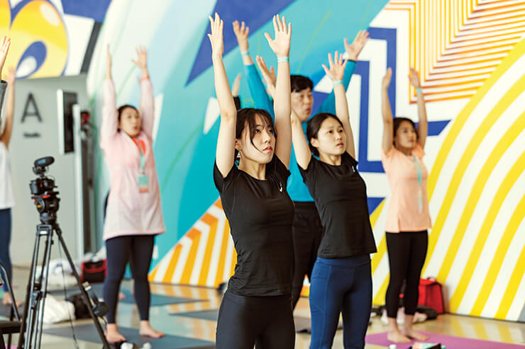 참가자들이 강하나 강사의 스트레칭 동작을 보며 열심히 따라 하고 있다.