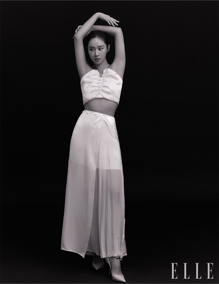 슬리브리스 톱은 LVIR. 스커트는 Ports 1961. 슈즈는 Jimmy Choo. 귀 아래쪽 이어 커프는 Sentiments. 귓바퀴 이어 커프는 The Part Of. 오른손 중지 링은 Engbrox. 검지링은 Le Haul.