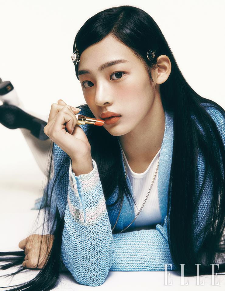 풍부한 레드 까멜리아 성분이 스킨케어 효과를 선사하는 N°1 DE CHANEL 레드 까멜리아 파운데이션으로 민지의 피부에 생기를 준다. 레 베쥬 워터-프레시 블러셔, 라이트 피치를 손끝에 묻혀 양볼과 콧등, 눈꺼풀까지 가볍게 터치해 싱그러운 살굿빛으로 물들인 뒤, 루쥬 코코 밤, 916 플러티 코랄을 입술에 발라 맑은 컬러감을 표현한다. 사용 제품은 모두 Chanel. 하늘색 롱 카디건과 메리 제인 슈즈, 헤어핀과 네크리스는 모두 Chanel. 이너 웨어로 입은 화이트 톱과 니 삭스는 모두 스타일리스트 소장품.