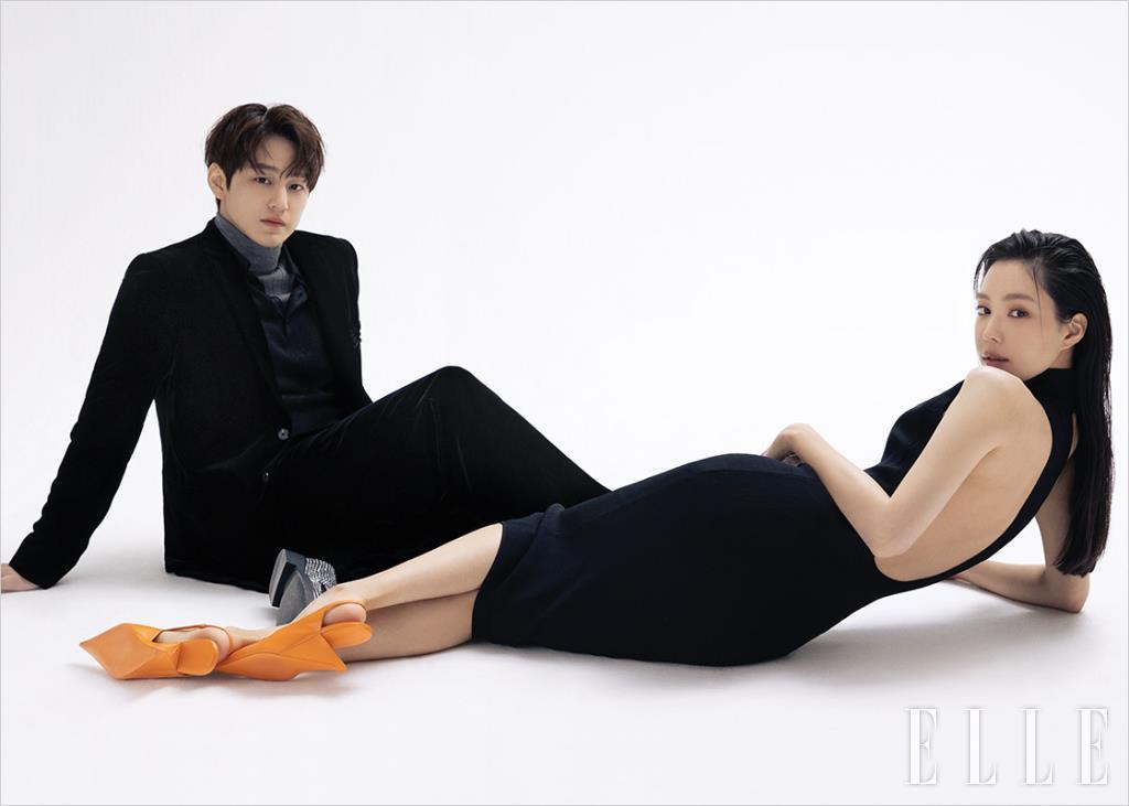 김범이 입은 그레이 터틀넥과 피케 니트 톱, 벨벳 재킷, 팬츠, 크리스털 로퍼는 모두 Prada. 손나은이 입은 블랙 드레스는 Solace London by Net-A-Porter. 오렌지 컬러 펌프스는 Prada.