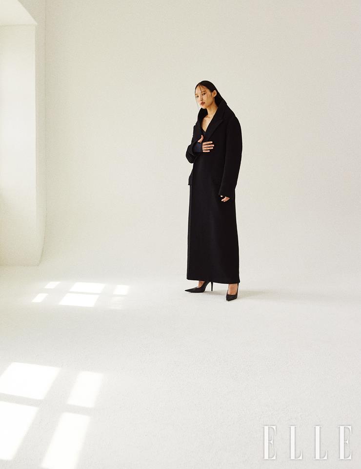  조형적인 실루엣의 블랙 맥시 코트와 랩 디테일의 톱, 스틸레토 힐은 가격 미정, 모두 Balenciaga. 