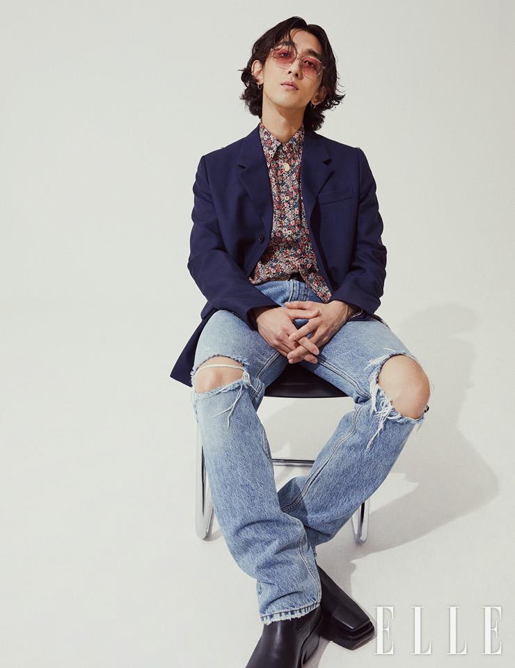 최정훈이 입은 네이비 재킷은 Prada. 플라워 패턴의 셔츠와 디스트로이드 데님 팬츠는 모두 Gucci. 쎄뻥 보헴 네크리스는 Boucheron. 틴티드 선글라스는 Gentle Monster. 슈즈는 Bottega Veneta. 벨트와 이어링은 스타일리스트 소장품. 