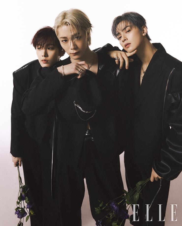 산하가 입은 레더 트리밍 블랙 재킷과 블랙 팬츠 모두 Vibrate. 문빈이 입은 블랙 재킷과 와이드 팬츠, 실버 체인 디테일의 볼캡 모두 Vibrate. 은우가 입은 컷아웃 디테일의 블랙 재킷과 팬츠 모두 Vibrate.