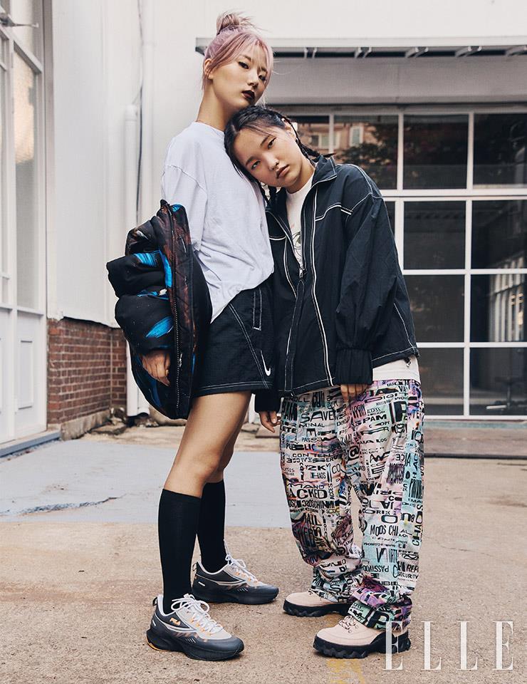 지연이 입은 화이트 티셔츠는 Meek Mild. 패딩 재킷은 Moschino. 스티치 디테일의 쇼트 스커트와 슈즈는 모두 Nike. 삭스는 스타일리스트 소장품. 윤경이 입은 집업 재킷은 Ganni. 패턴 와이드 팬츠는 Moschino. 슈즈는 Fila.