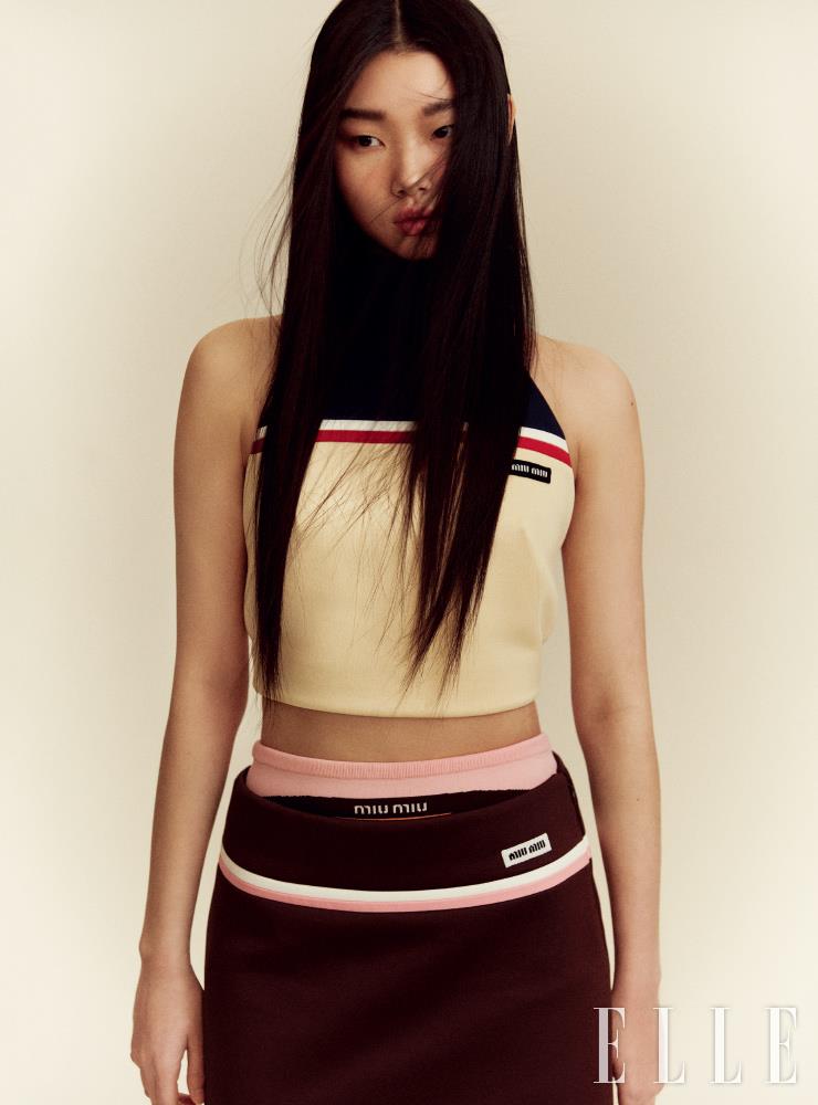 스포티한 홀터넥 톱과 미디스커트, 이너 웨어로 입은 핑크 쇼츠는 모두 Miu Miu.