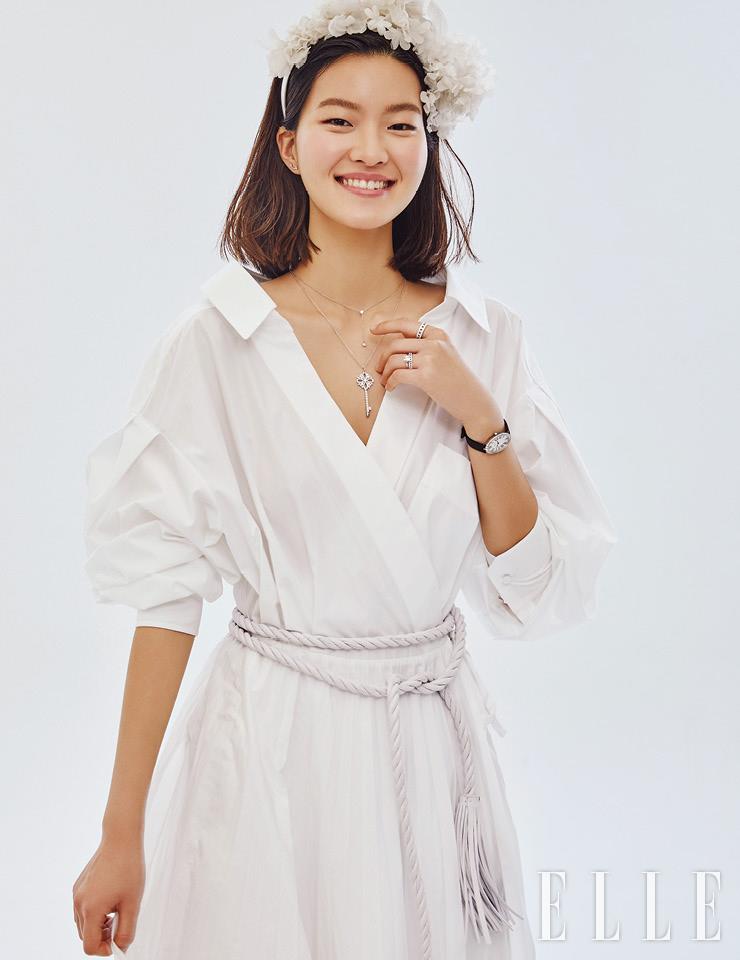 티파니 티 스마일 이어링과 Y자 형태로 늘어지는 펜던트의 티파니 엘사 페레티 다이아몬드 바이 더 야드 네크리스, 티파니 빅토리아 키 펜던트 네크리스, 심플한 플래티넘 위에 다이아몬드를 세팅한 티파니 트루 링, 연속적으로 맞물린 T 형태가 그래픽적인 티파니 티 트루 파베 내로 링과 티파니 티 트루 파베 와이드 링, 타원형 케이스에 48개의 다이아몬드를 세팅한 티파니 칵테일 워치는 가격 미정, 모두 Tiffany & Co. 화이트 셔츠 드레스는 3백80만원, Valentino. 벨트는 55만원, Valentino Garavani. 풍성한 플라워 장식의 헤어밴드는 가격 미정, The Queen Lounge. 