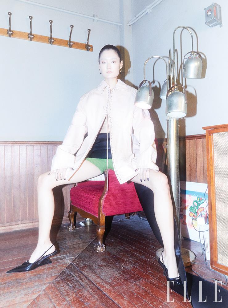 코르셋 디테일의 재킷과 미니스커트, 레이어드해서 입은 그린 쇼츠, 구조적인 힐의 슬링백은 가격 미정, 모두 Prada. 구슬 장식의 이어링은 3만9천원, COS.