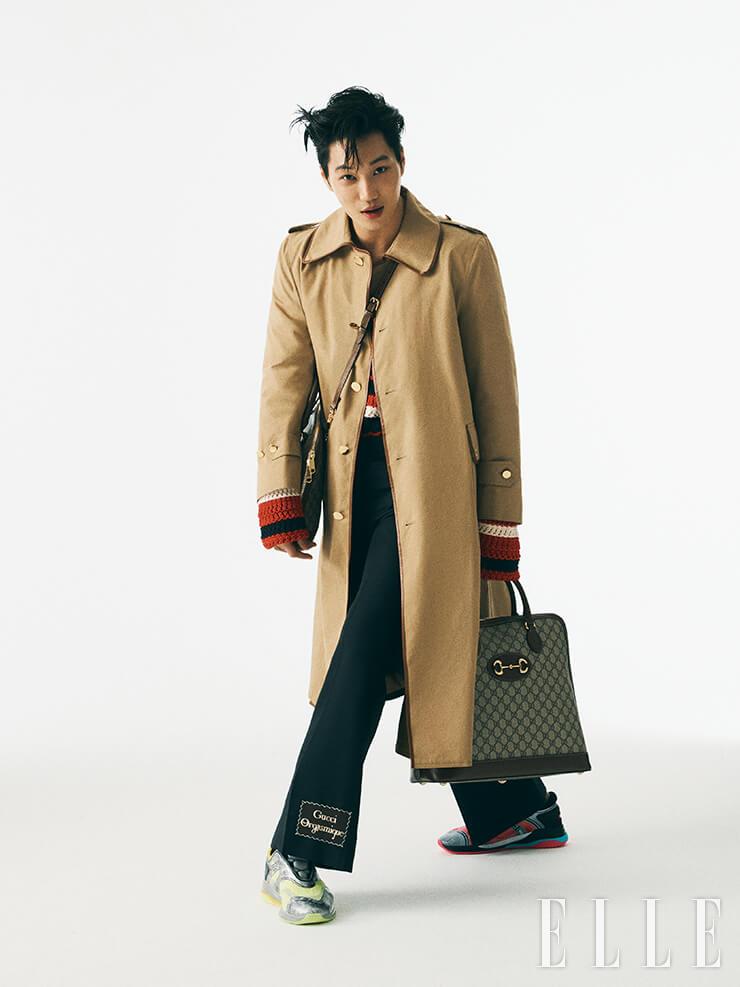 트렌치코트와 레드 컬러 니트 톱, 로고 장식의 부츠 컷 팬츠, GG 로고 패턴의 1955 홀스빗 백, 양쪽이 다른 컬러의 스니커즈는 모두 Gucci.
