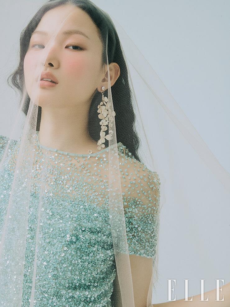 민트 컬러의 스팽글 드레스는 Escada Vintage Gown. 꽃 모티프의 싱글 이어링은 Angtt. 핑크 베일은 Esmeralda. 