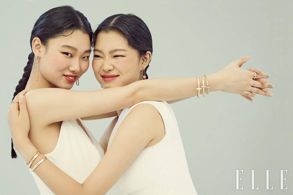  윤영의 티파니 하드웨어 더블 롱 링크 이어링과 티파니 T1 와이드 하프 다이아몬드 힌지드 뱅글, 티파니 T1 와이드 풀 다이아몬드 힌지드 뱅글, 티파니 T 컬러 와이어 브레이슬렛, 검지의 티파니 T1 와이드 풀 다이아몬드 링, 중지의 티파니 T 와이어 FC링, 약지에 레이어드한 티파니 T1 내로 하프 다이아몬드 링과 티파니 T1 내로 링은 모두 Tiffany & Co. 슬립 드레스는 Leemyungsoon Wedding. 윤지가 착용한 티파니 하드웨어 트리플 드롭 이어링과 약지의 다이아몬드 세팅 티파니 T 트루 파베 내로 링, 검지의 티파니 T 와이어 링, 가느다란 18K 옐로골드 커프 위에 다이아몬드를 장식한 티파니 T 와이어 브레이슬렛, 한 줄로 다이아몬드를 세팅한 티파니 T투 힌지드 브레이슬렛과 다이아몬드를 파베 세팅한 티파니 T투 힌지드 브레이슬렛은 모두 Tiffany & Co. 원 숄더 드레스는 Bridal Kong.