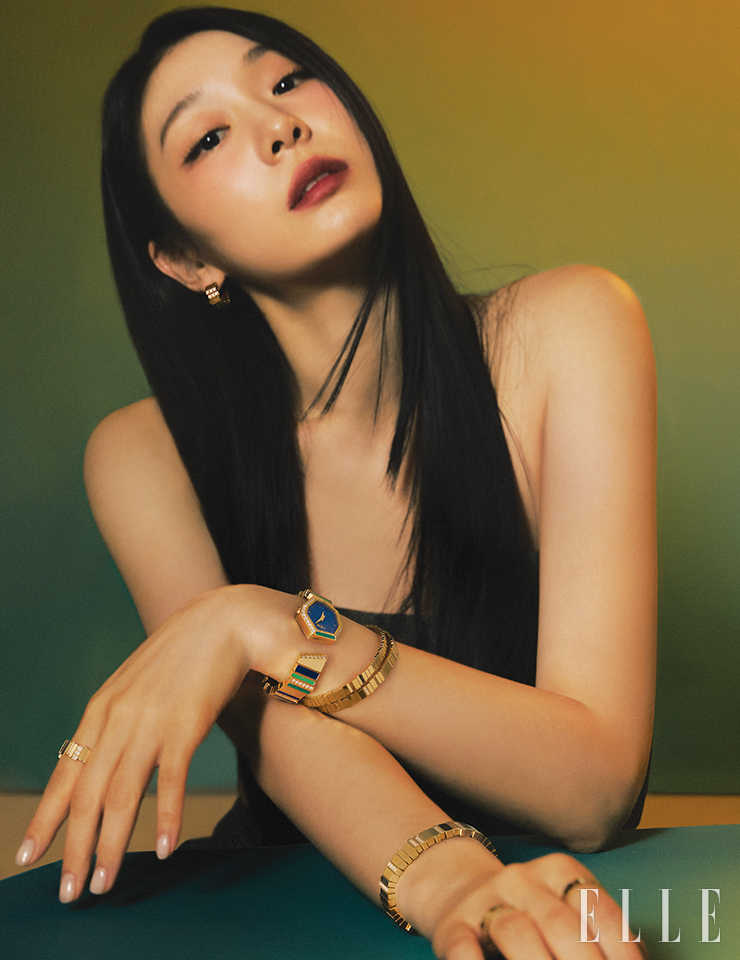 옐로골드에 크리소프레이즈와 라피스 라줄리, 말라카이트를 세팅한 ‘젬 디올’ 타임피스는 Dior Timepiece. 옐로골드에 0.44 캐럿 다이아몬드를 세팅한 ‘젬 디올’ 이어링과 왼손에 착용한 옐로골드 ‘젬 디올’ 브레이슬릿, 옐로골드에 0.22캐럿 다이아몬드를 세팅한 ‘젬 디올’ 브레이슬릿, 왼손 검지에 낀 옐로골드에 0.5 캐럿 다이아몬드를 세팅한 ‘젬 디올’ 링, 오른쪽 손목에 착용한 와이드 버전의 옐로골드 ‘젬 디올’ 브레이슬릿, 오른손 검지에 낀 0.14캐럿 다이아몬드 세팅 옐로골드 ‘젬 디올’ 링, 약지에 낀 옐로골드 ‘젬 디올’ 링은 모두 Dior Joaillerie. 튜브 톱은 Dior.