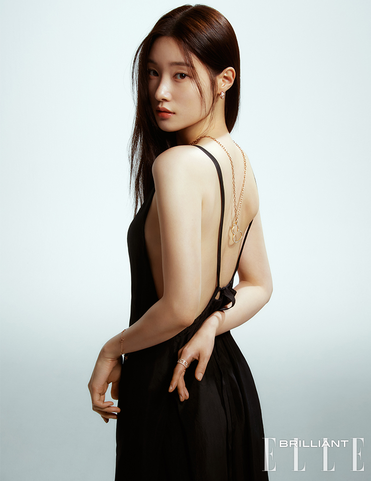 다이아몬드를 세팅한 ‘울루 후프’ 이어링, 길이 조절이 가능한 체인 네크리스, 미디엄 사이즈의 ‘울루’ 펜던트, 왼팔에 착용한 다이아몬드와 레드 에나멜 세팅의 ‘울루 소투아르’ 브레이슬릿, 오른손 검지에 착용한 ‘울루’ 링은 모두 QEELIN. 백리스 드레스는 DEMOO.