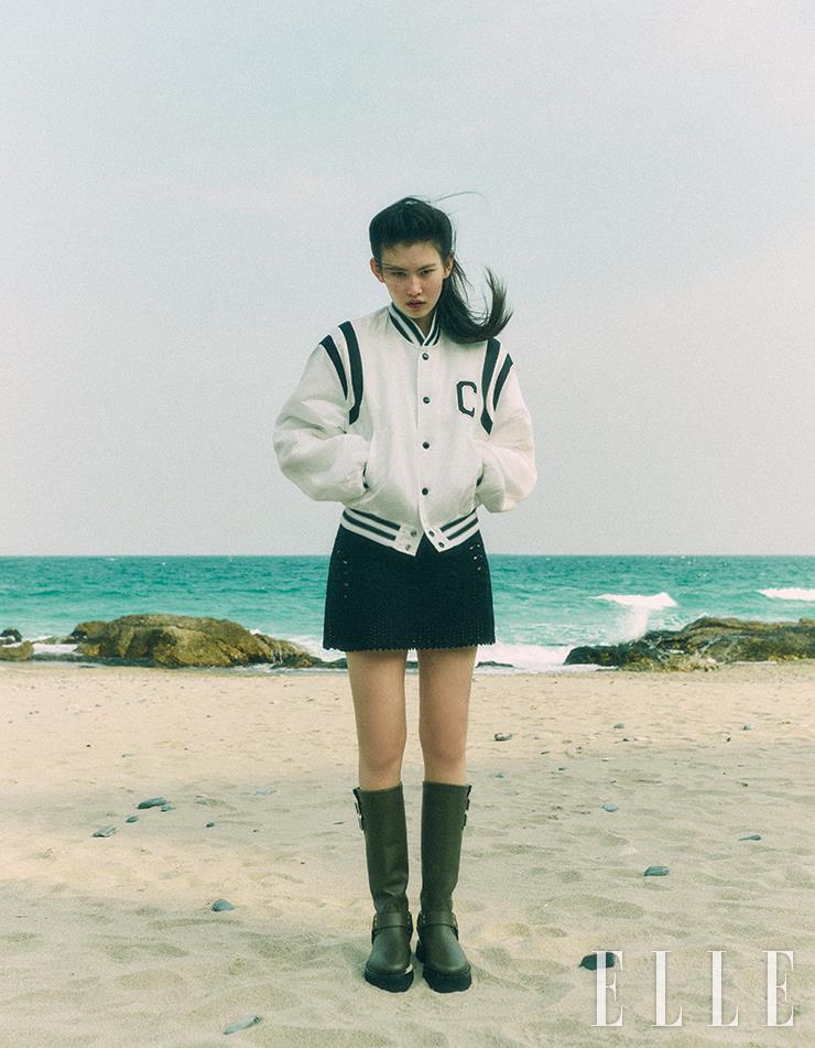 C 로고 스타디움 재킷과 크로셰 원피스, 브라운 바이커 부츠는 모두 Celine by Hedi Slimane.