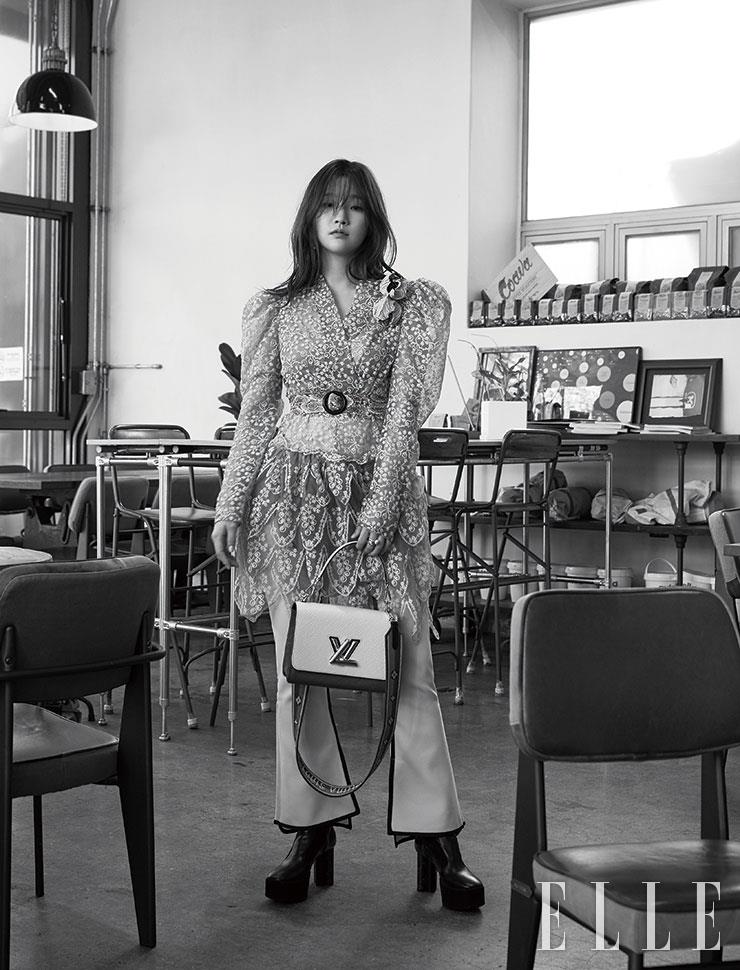 레이스 소재의 티어드 미니 원피스와 테이핑 장식의 부츠 컷 팬츠, 플랫폼 부츠, 와이드 스트랩이 특징인 트위스트 & 트위스티 백. 레이어드한 B 블라썸 파인 주얼리 링은 모두 Louis Vuitton.