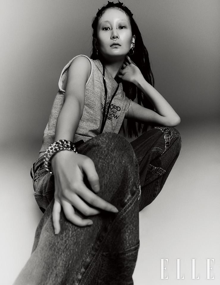  그레이 슬리브리스 티셔츠와 패치 디테일의 와이드 데님 팬츠는 가격 미정, 모두 Tom Ford. 골드 뱅글은 가격 미정, Chanel. 카드 홀더 네크리스는 25만원, Off-White&trade;. 하트 후프 이어링은 7만8천원, Pandora. 실버 이어 커프는 17만5천원, Portrait Report. 