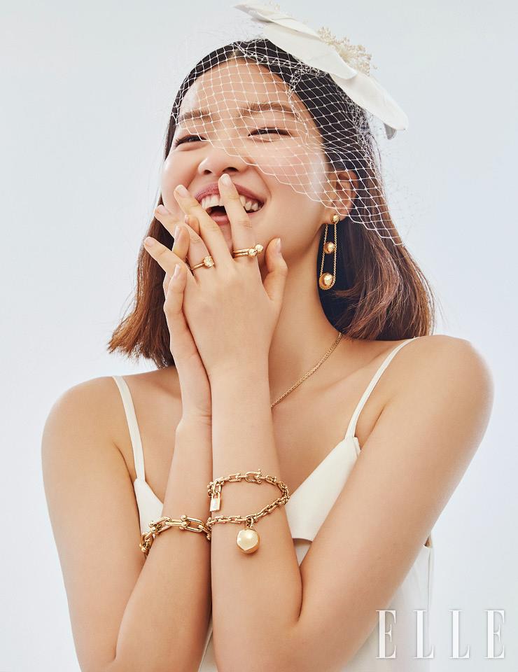 약지에 착용한 팬시 옐로 모디파이드 브릴리언트 다이아몬드를 세팅한 티파니 트루 링과 검지에 두 개를 레이어드한 티파니 하드웨어 볼 링, 티파니 하드웨어 트리플 드롭 이어링, 티파니 하드웨어 더블 링크 펜던트 네크리스, 오른팔의 볼드한 체인 모티프 티파니 하드웨어 라지 링크 브레이슬렛, 왼팔의 볼과 록 장식이 대담한 티파니 하드웨어 랩 브레이슬렛은 가격 미정, 모두 Tiffany & Co. 슬립 드레스는 가격 미정, Jaybaek Couture. 샤 디테일의 플라워 헤어피스는 가격 미정, Angtt. 