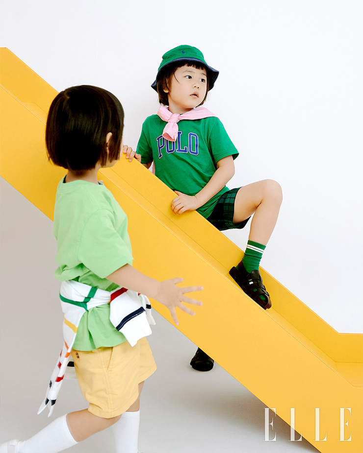 이준이 입은 그린 코튼 저지 크루넥티, 레이어드한 블루 크루넥 티, 허리에 두른 스트라이프 코튼 저지 럭비 셔츠,옐로 컬러 코튼 쇼츠는 모두 Polo Ralph Lauren. 신우가 입은 폴로 타이포 로고 그린 티셔츠와 어깨에 두른 핑크 리넨 셔츠, 플래드 시어서커 쇼츠, 그린 버킷햇은 모두 Polo Ralph Lauren.