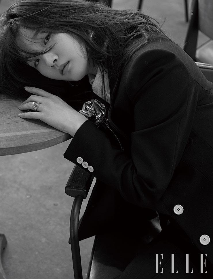 화이트 버튼 장식의 네이비 수트와 화이트 셔츠, 골드 이어링과 링은 모두 Louis Vuitton.