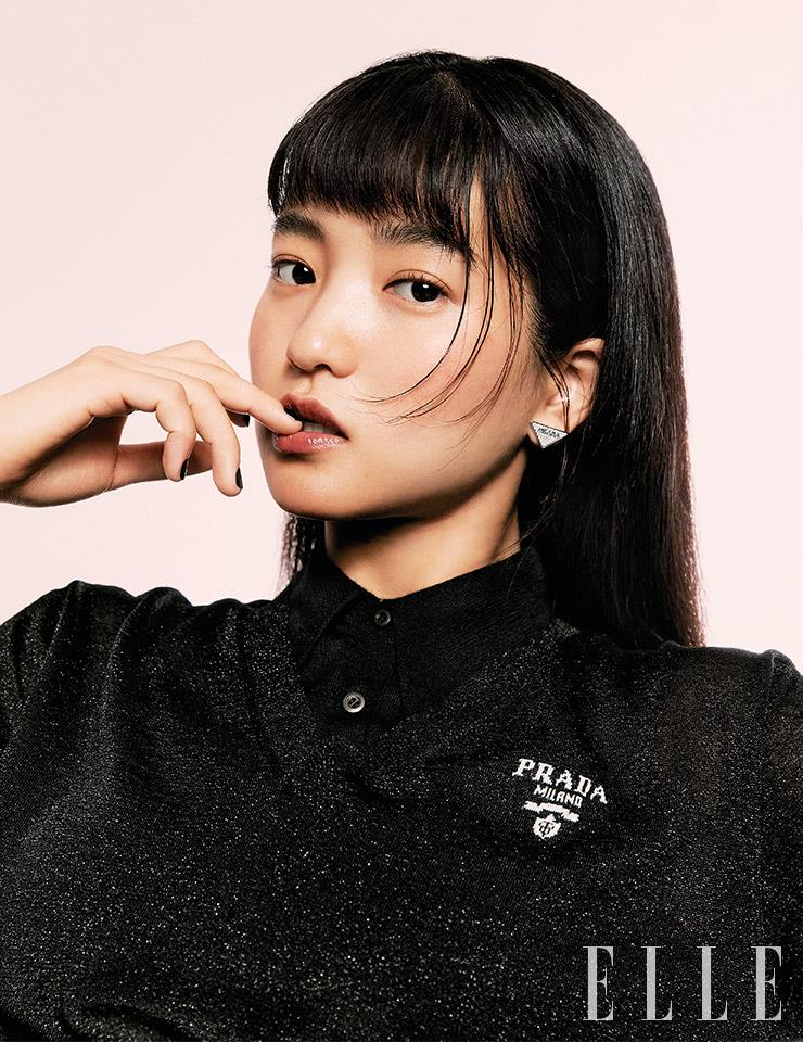 블랙 니트 드레스와 슬리브리스 톱, 삼각 로고 이어링은 모두 Prada.