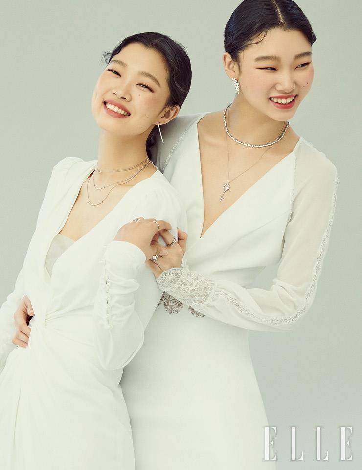 윤지가 착용한 티파니 T 와이어 바 이어링과 웃는 입 모습을 형상화한 티파니 T 스마일 미니, 미디엄, 라지 펜던트 네크리스, 검지의 다이아몬드를 풀 세팅한 티파니 T 와이어 FC링, 약지의 티파니 T투 내로 링과 티파니 T 트루 와이드 링은 모두 Tiffany & Co. 미니멀한 드레스는 Monique Lhuillier by Soyoo Bridal. 윤영의 티파니 빅토리아 믹스드 클러스터 드롭 이어링과 티파니 빅토리아 그레듀에이티드 라인 네크리스, 레이어드한 티파니 빅토리아 바인 서클 키 펜던트, 검지의 티파니 빅토리아 바인 링, 약지의 라운드 브릴리언트 컷 티파니 세팅 링과 티파니 솔리스트 브이 밴드 링은 가격 미정, 모두 Tiffany & Co. 레이스 디테일의 드레스는 Rosa Clara by Esmeralda.