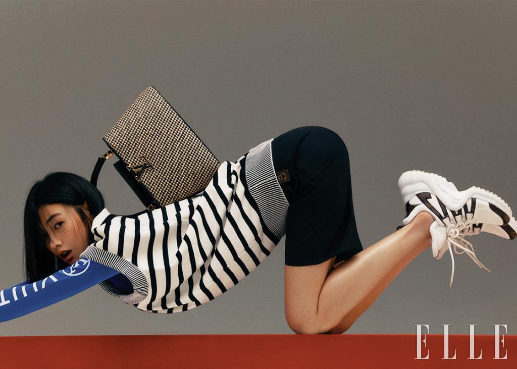 라피아 소재의 블랙 & 베이지 컬러 ‘카퓌신PM’ 백, 스트라이프 니트 베스트와 로고 톱, 버뮤다 쇼츠, ‘LV아치라이트’ 스니커즈는 모두 Louis Vuitton.