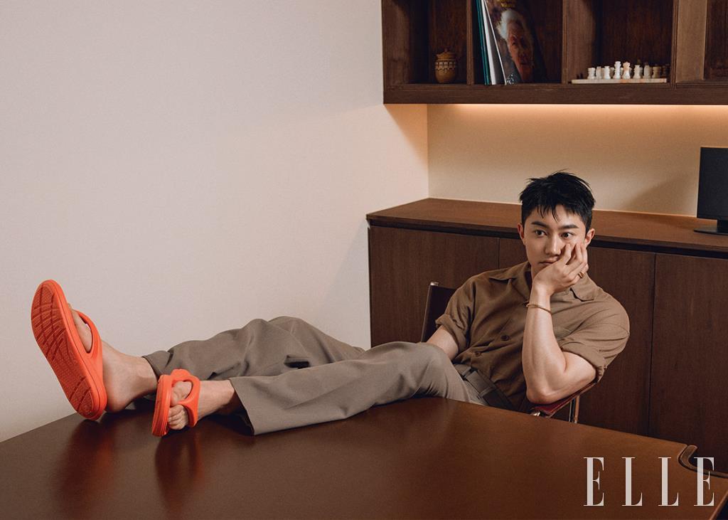 셔츠와 벨티드 와이드 팬츠는 모두 Lemaire. 플립플롭은 Fila. 브레이슬렛은 Portrait Report.