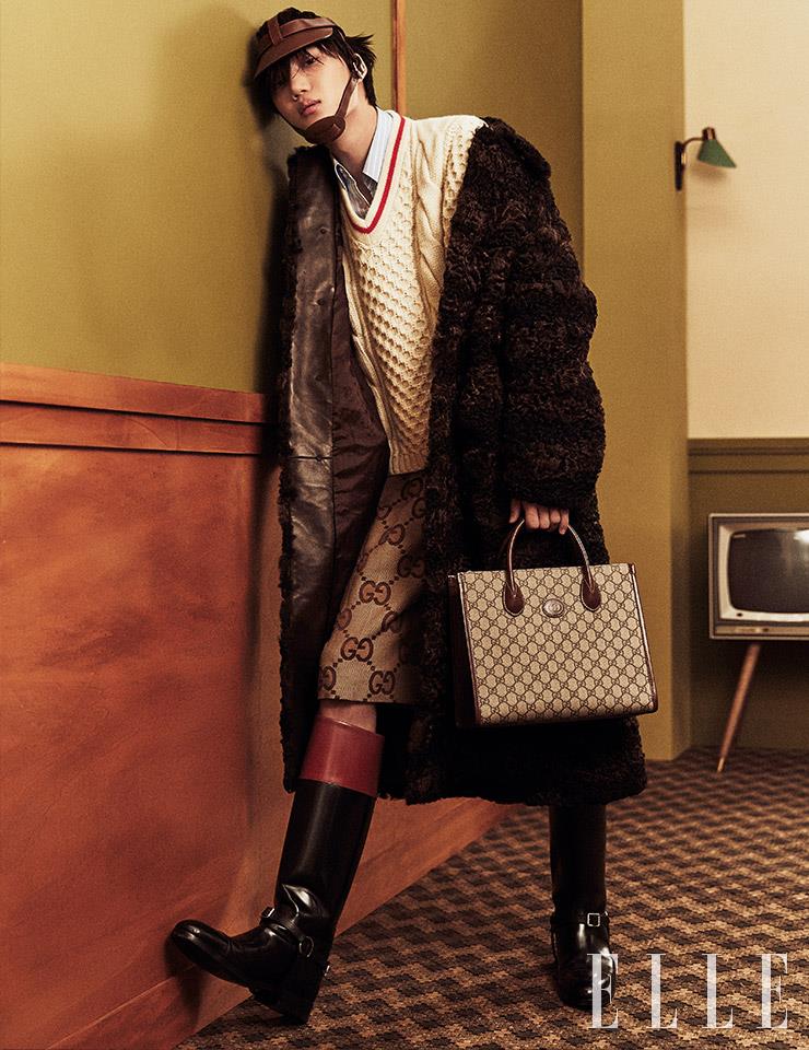 시어링 코트와 니트 베스트, 스트라이프 셔츠, 모노그램 패턴의 팬츠, GG 수프림 캔버스 스몰 토트백, 롱부츠, 가죽 헤드기어는 모두 Gucci.