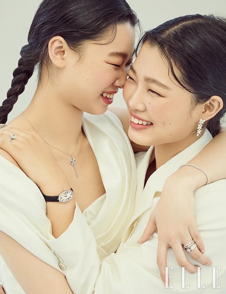 윤영의 빅토리아 키 펜던트, 티파니 빅토리아 라인 브레이슬렛, 연속적으로 맞물린 T 형태가 그래픽적인 티파니 T 트루 와이드 링과 티파니 T투 내로 링은 가격 미정, 모두 Tiffany & Co. 오프숄더 재킷은 Dana Harel by Maison Reve. 윤지의 티파니 빅토리아 믹스드 클러스터 드롭 이어링, 플래티넘 위에 트루 컷 화이트 다이아몬드를 더한 티파니 트루 링, 촘촘하게 맞물린 T 형태가 구조적인 티파니 T 트루 파베 내로 링, 48개의 라운드 컷 다이아몬드를 세팅한 티파니 칵테일 워치는 가격 미정 모두 Tiffany & Co. 화이트 재킷은 JW Anderson. 