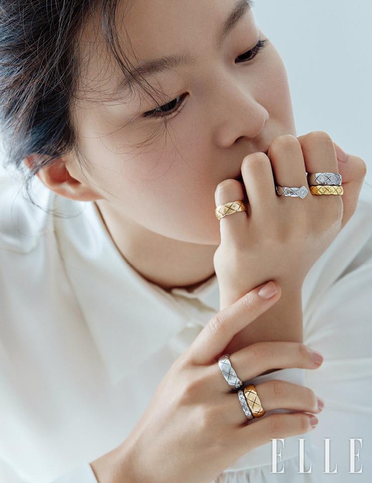 왼손 새끼손가락의 베이지골드 코코 크러쉬 스몰 링, 중지와 검지에 착용한 더블 링 형태의 코코 크러쉬 링, 검지에 레이어드한 다이아몬드 세팅 화이트골드 코코 크러쉬 스몰 링과 오른손 중지의 화이트골드 코코 크러쉬 스몰 링, 약지에 레이어드한 베이지골드 코코 크러쉬 스몰 링과 화이트골드 코코 크러쉬 미니 링은 모두 Chanel Fine Jewelry.