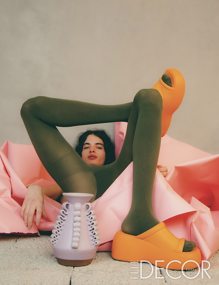 구불거리는 장식이 매력적인 핑크색 화병 ‘롤라 베이스 에이(Lola Vase A)’는 Perla Valtierra. 산뜻한 오렌지색 샌들은 Bimba Y Lola.