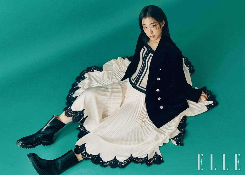 벨벳 소재의 블랙 재킷, 니트 톱, 플리츠스커트는 모두 EENK. 블랙 부츠는 Jimmy Choo.